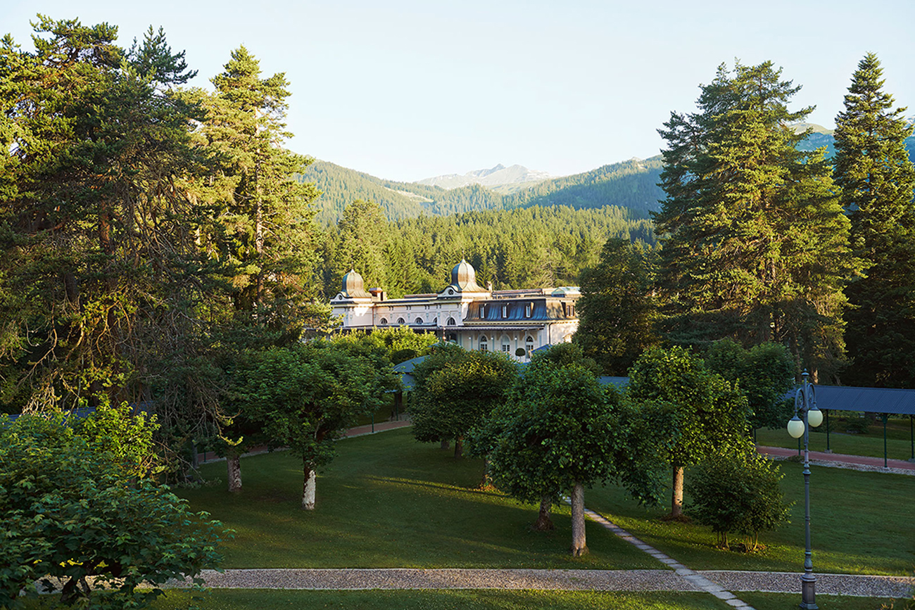 beautiful shot of the Belle Époque pavilion surrounded by nature, trees, grass lawn and mountain views and clear blue sky