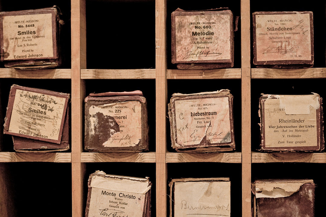 a detail shot of an exhibit in the Belle Epoque museum at the resort. There are wooden square shelves that hold old, tattered boxes. Each box has a label explaining what it was used for.